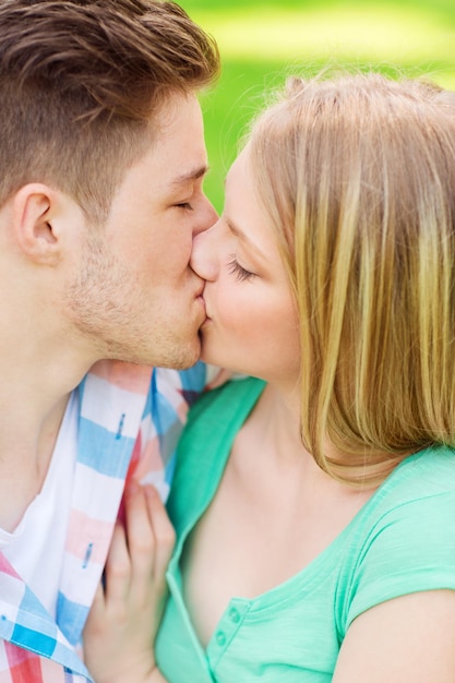 concetto di vacanze, vacanze, amore e amicizia - coppia sorridente che si bacia e si abbraccia nel parco