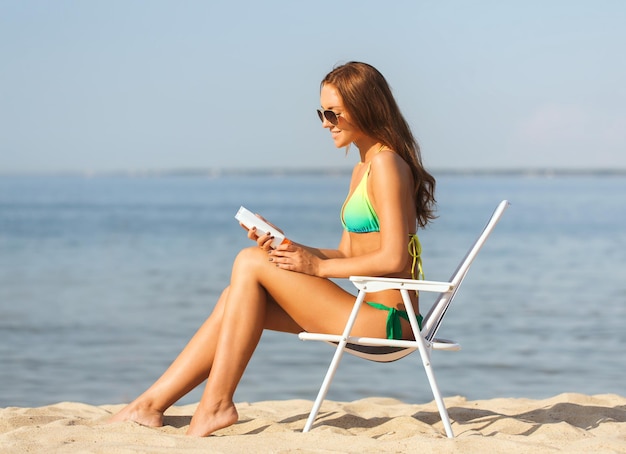 concetto di vacanze, vacanze e persone estive - giovane donna sorridente che prende il sole nella lounge sulla spiaggia