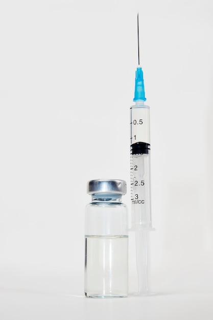 Concetto di vaccinazione medica con siringa e fiale mediche. Bottiglia di vaccino e iniezione di siringhe su sfondo bianco con spazio di copia, primo piano