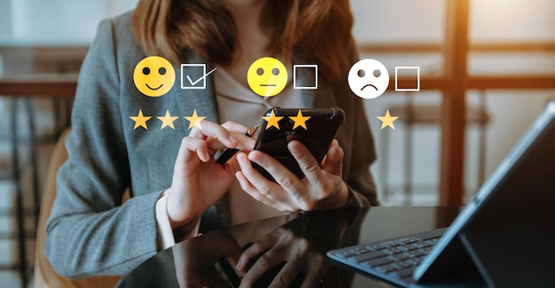 Concetto di valutazione del servizio clienti Donna d'affari che preme lo spettacolo di emoticon sorriso viso sullo schermo virtuale su tablet e smartphone in ufficio