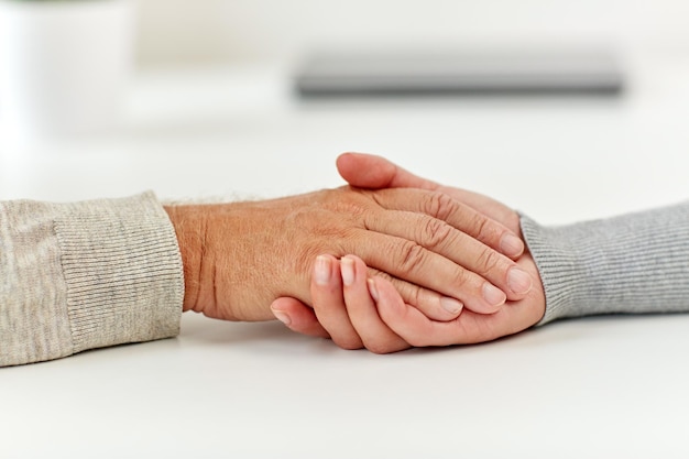 concetto di vecchiaia, sostegno, beneficenza, cura e persone - primo piano di uomo anziano e giovane donna che si tengono per mano