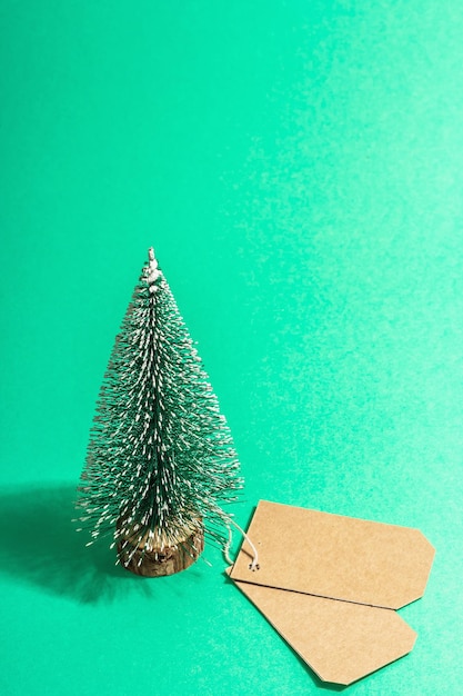 Concetto di vendita di Natale su sfondo turchese. Etichetta decorativa dell'albero di abete e della carta. Simbolo tradizionale del nuovo anno. Una luce dura alla moda, un'ombra scura. Disposizione piatta, mockup, modello, primo piano