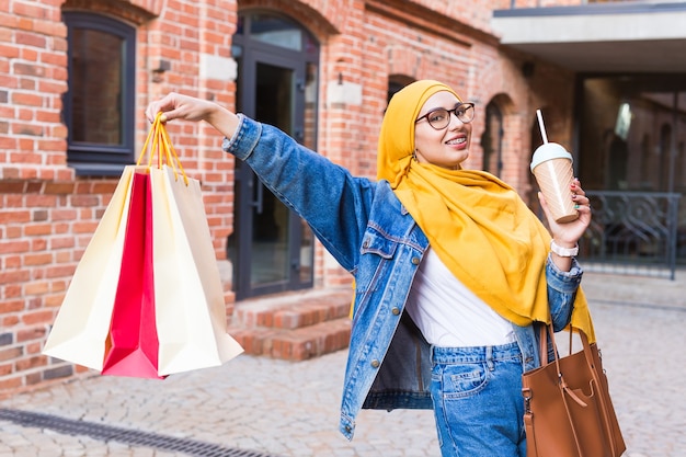 Concetto di vendita e acquisto - ragazza musulmana abbastanza araba con borse della spesa dopo il centro commerciale