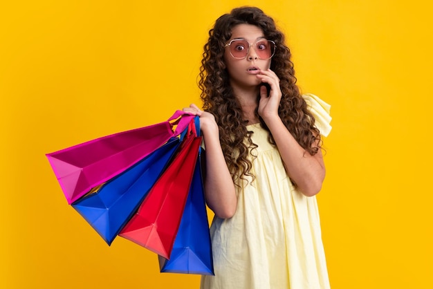 Concetto di vendita e shopping Ragazza teenager che tiene borse della spesa isolate su sfondo di studio Il viso stupito scioccato ha sorpreso le emozioni della ragazza adolescente Vendita di shopping estivo