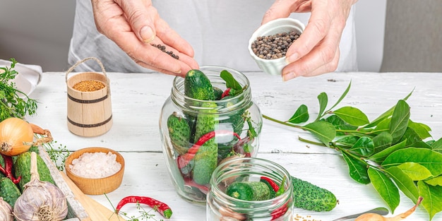 Concetto di verdure di stagione conservate Raccolta di cetriolo, peperoncino, cipolla e aglio Le mani della donna preparano gli ingredienti per il processo di cottura casalinga del cibo in scatola Formato banner ricette sane