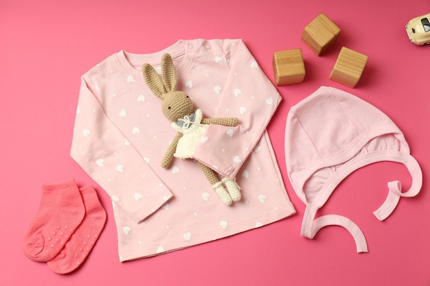 Concetto di vestiti per bambini femminili su sfondo rosa.