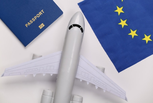 Concetto di viaggio. Aereo passeggeri, passaporto e bandiera dell'Unione europea su sfondo bianco