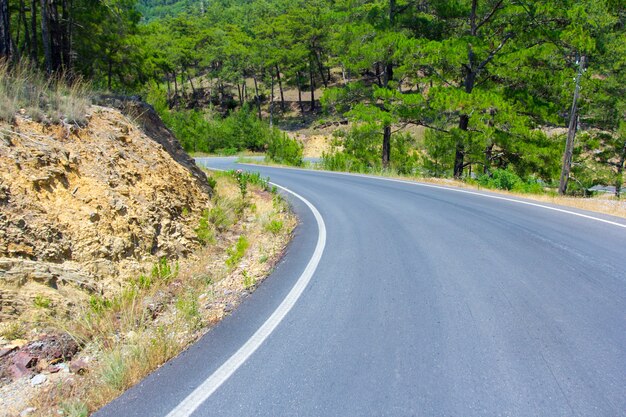 Concetto di viaggio e viaggio su strada - strada asfaltata curva nella foresta di montagna