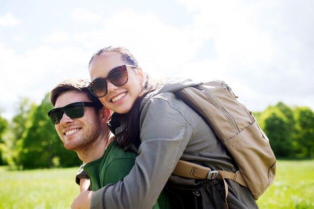 concetto di viaggio, escursionismo, zaino in spalla, turismo e persone - coppia felice in occhiali da sole con zaini che si divertono all'aperto