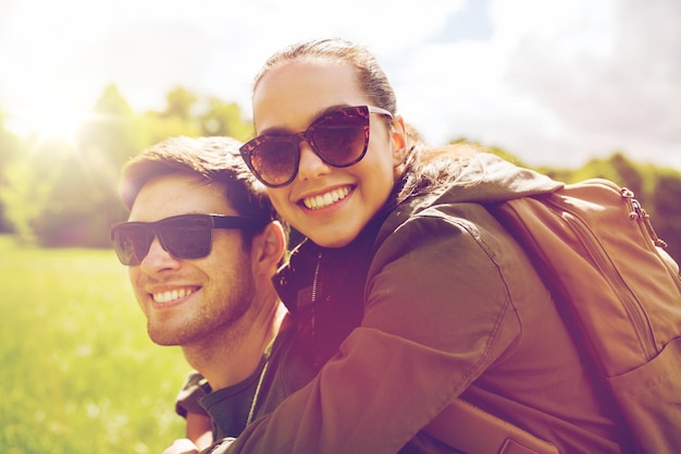 concetto di viaggio, escursionismo, zaino in spalla, turismo e persone - coppia felice in occhiali da sole con zaini che si divertono all'aperto