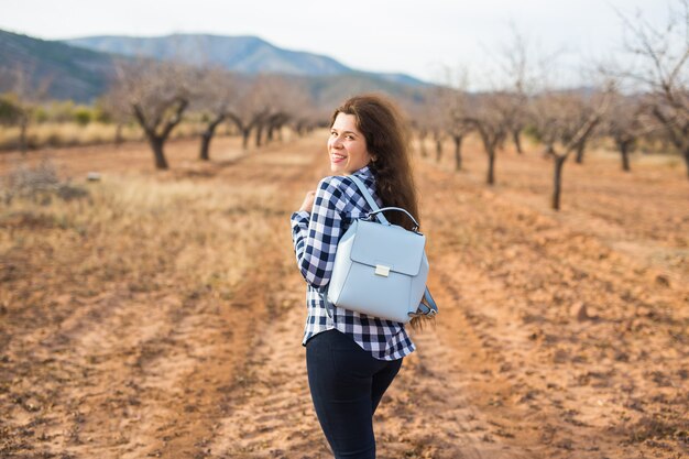 Concetto di viaggio, estate e persone. donna con zaino elegante sullo sfondo della natura. Lei è in vacanza