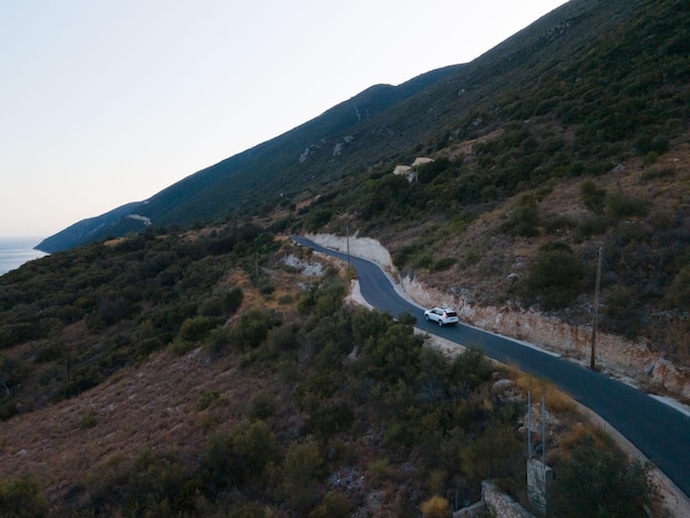 Concetto di viaggio in auto che si muove su strada in montagna con vista sulla riva del mare