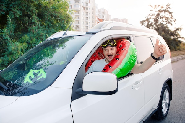 Concetto di viaggio in auto per vacanze in mare uomo in maschera subacquea che guida un'auto piena di borse