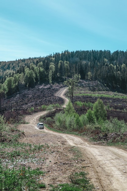 Concetto di viaggio in auto suv che guida su una strada di campagna che porta alle montagne