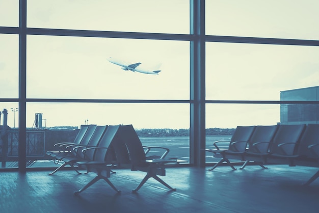 Concetto di viaggio interno vuoto della lounge dell'aeroporto sullo sfondo dell'effetto filtro blu degli aerei in volo