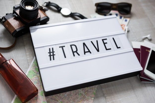 Concetto di viaggio primo piano di oggetti da viaggio e light box con hashtag travel