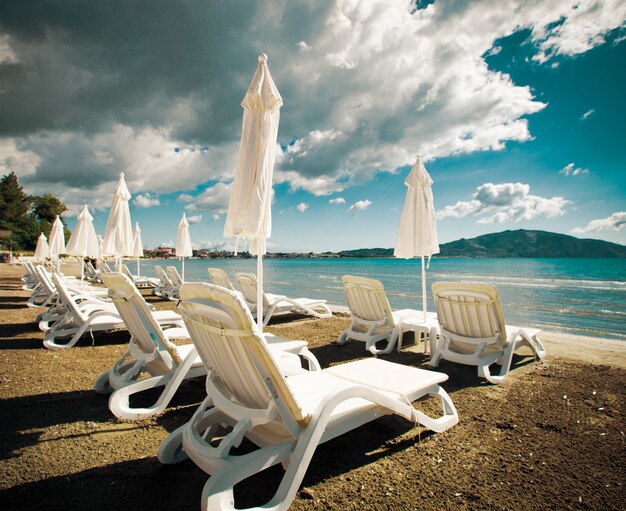 Concetto di viaggio - sedie a sdraio con ombrelloni sulla bellissima spiaggia, isola di Zante, Grecia