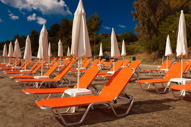 Concetto di viaggio - sedie a sdraio con ombrelloni sulla bellissima spiaggia, isola di Zante, Grecia