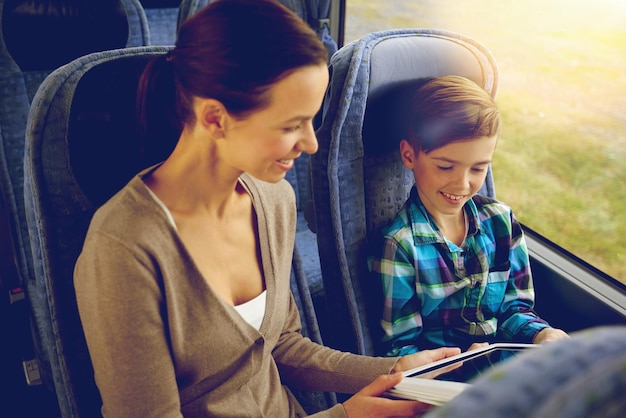 concetto di viaggio, turismo, famiglia, tecnologia e persone - madre e figlio felici con computer tablet pc seduto in autobus di viaggio