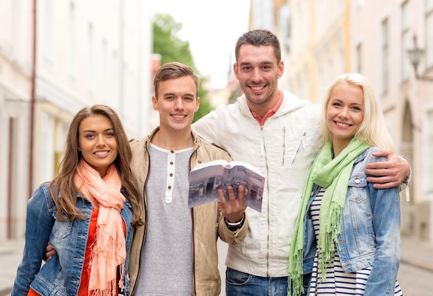 concetto di viaggio, vacanza e amicizia - gruppo di amici sorridenti con guida della città che esplora la città