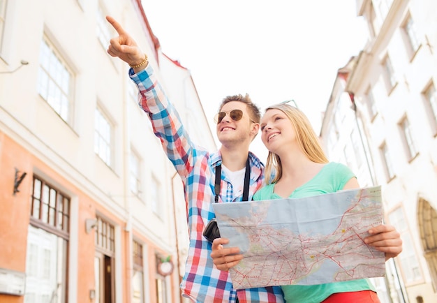 concetto di viaggio, vacanza, tecnologia e amicizia - coppia sorridente con mappa e macchina fotografica che esplorano la città