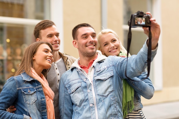 concetto di viaggio, vacanza, tecnologia e amicizia - gruppo di amici sorridenti che fanno selfie con la fotocamera digitale all'aperto