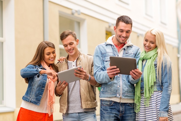 concetto di viaggio, vacanza, tecnologia e amicizia - gruppo di amici sorridenti con computer tablet pc in città