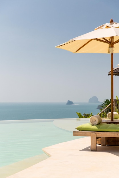concetto di viaggio, vacanza, turismo e lusso - splendida vista dalla piscina a sfioro con ombrellone in riva al mare