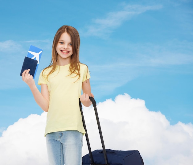 concetto di viaggio, vacanza, vacanza, infanzia e trasporto - bambina sorridente con valigia, biglietto aereo e passaporto