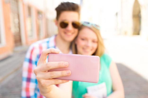 concetto di viaggio, vacanze estive, tecnologia e amore - primo piano di una coppia felice che si fa selfie con lo smartphone in città