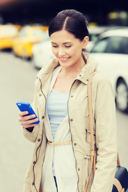 concetto di viaggio, viaggio d'affari, persone e turismo - giovane donna sorridente con smartphone sopra la stazione dei taxi o una strada cittadina