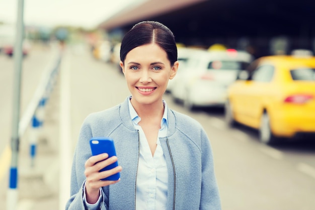 concetto di viaggio, viaggio d'affari, persone e turismo - giovane donna sorridente con smartphone sopra la stazione dei taxi o una strada cittadina