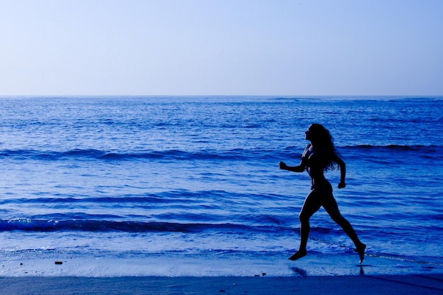 Concetto di vita sana donna sportiva che corre lungo la spiaggia