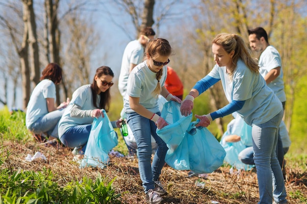 concetto di volontariato, beneficenza, pulizia, persone ed ecologia - gruppo di volontari felici con l'area di pulizia dei sacchi della spazzatura nel parco