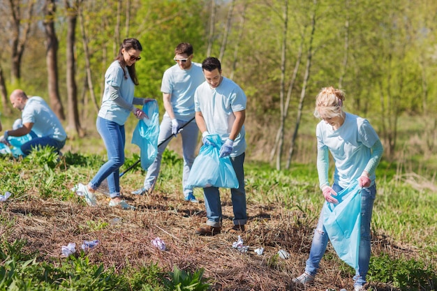 concetto di volontariato, beneficenza, pulizia, persone ed ecologia - gruppo di volontari felici con l'area di pulizia dei sacchi della spazzatura nel parco