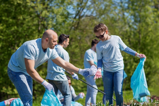 concetto di volontariato, beneficenza, pulizia, persone ed ecologia - gruppo di volontari felici con l'area di pulizia dei sacchi della spazzatura nel parco