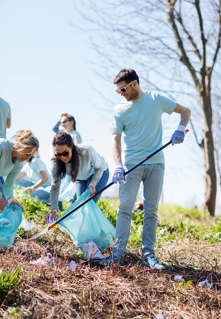 concetto di volontariato, beneficenza, pulizia, persone ed ecologia - gruppo di volontari felici con l'area di pulizia dei sacchi della spazzatura nel parco