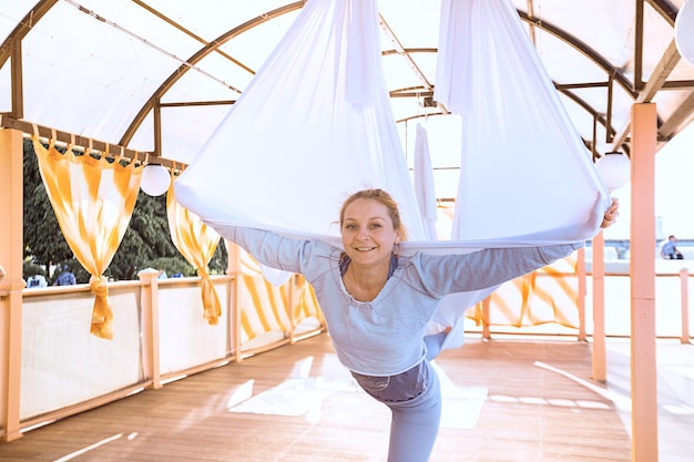 Concetto di yoga sano e volante. ragazza sorridente felice in una lezione di yoga fly