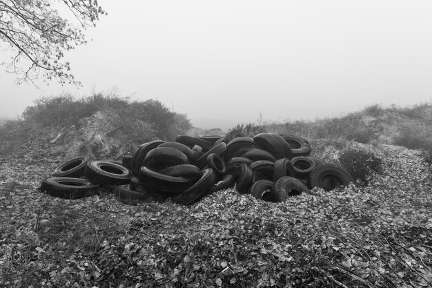 Concetto ecologico. Mucchio di vecchi pneumatici. Discarica di vecchi pneumatici usati in città in una nebbiosa giornata autunnale