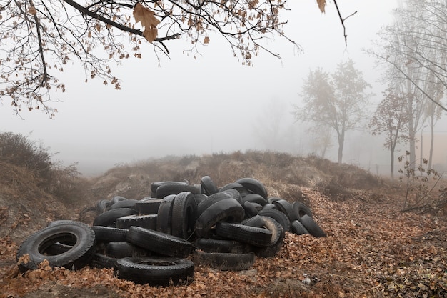 Concetto ecologico. Mucchio di vecchi pneumatici. Discarica di vecchi pneumatici usati in città in una nebbiosa giornata autunnale