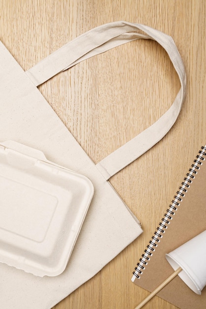Concetto ecologico Tazza di carta con quaderno di cannucce e scatole su borsa ecologica su sfondo di legno