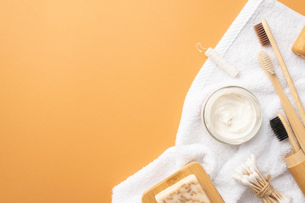 Concetto ecologico Vista dall'alto foto di accessori spa spazzolini da denti barattolo di dentifricio asciugamano di cotone bianco sapone su supporto in legno bastoncini di cotone e filo interdentale su sfondo beige isolato con copyspace