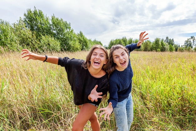 Concetto felice della gente di vacanza di vacanze estive. Un gruppo di due ragazze che ballano abbracciare e divertirsi insieme nella natura all'aperto. Momenti adorabili migliore amica.