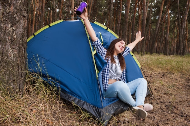 Concetto felice della tenda di rilassamento della donna. Pubblicità di attrezzature turistiche. Unità con la natura.