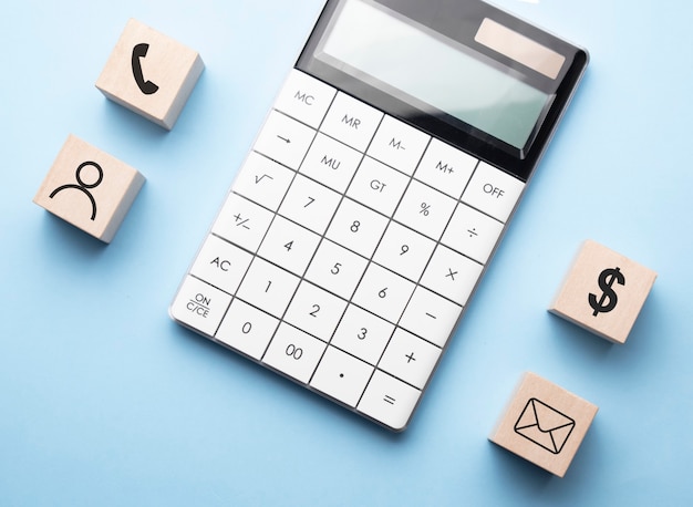 Concetto finanziario con icone su cubi di legno, calcolatrice su superficie blu