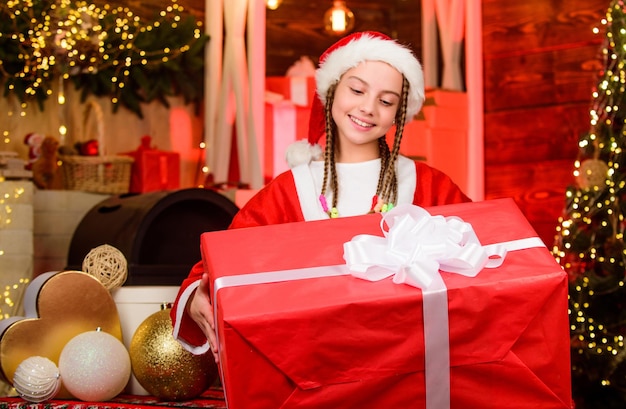 Concetto gratificante. Bambino che si diverte la vigilia di Natale. Felicità e gioia. Il costume da Babbo Natale della ragazza ha ricevuto un regalo. Equipaggio di Babbo Natale. Festa di Babbo Natale. Buon anno. Grande sorpresa. Presente d'inverno. Vacanza generosa.