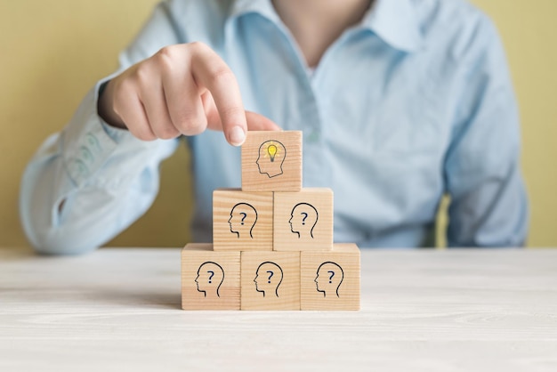 Concetto idea creativa e innovazione Blocco cubo di legno raccolto a mano con icona della lampadina sulla piramide superiore e simbolo umano della testa