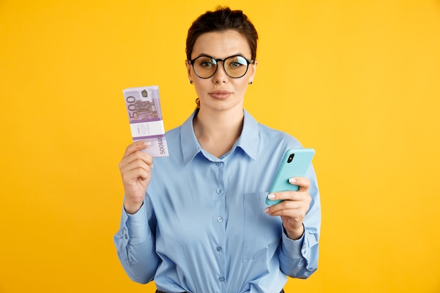 Concetto in linea di affari. donna in ufficio blu shurt tenendo soldi e telefono.