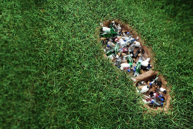Concetto inquinamento da plastica impronta umana nell'erba verde piena di rifiuti di plastica umanità