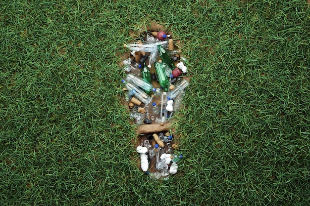Concetto inquinamento da plastica impronta umana nell'erba verde piena di rifiuti di plastica umanità